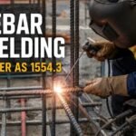 Construction site welder performing rebar welding on reinforcing steel bars with visible welding arc and sparks, featuring the title “Rebar Welding as per AS 1554.3” and highlighting why lower-strength filler metal is used for 500N rebar welding.